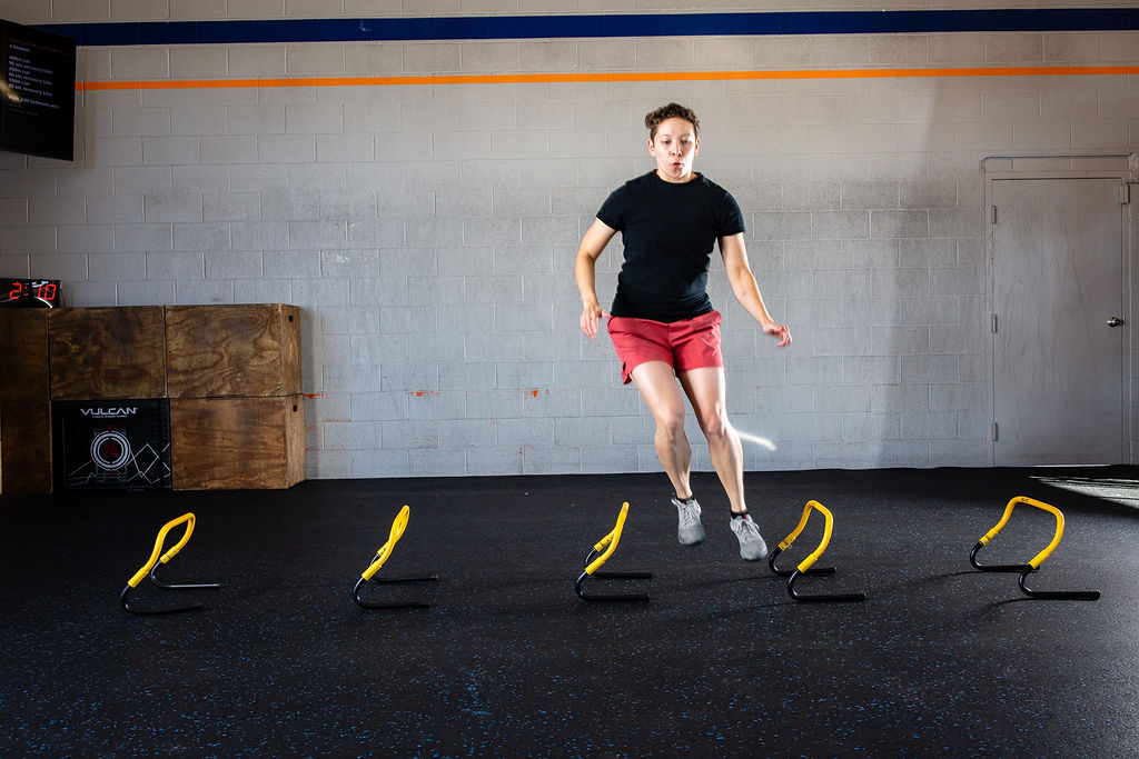 An athlete hopping over a line of training hurdles