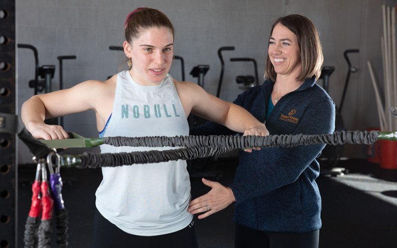 A physical therapist guiding a patient through a banded pull